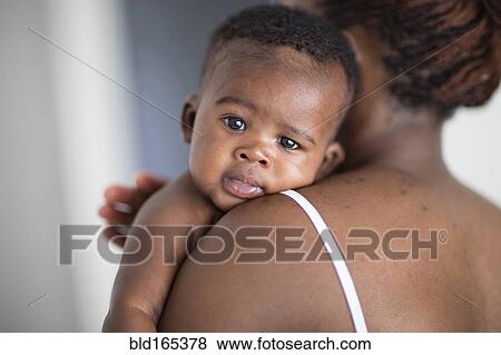 Stock Photo - Close up of Black mother burping baby over her shoulder. Fotosearch
