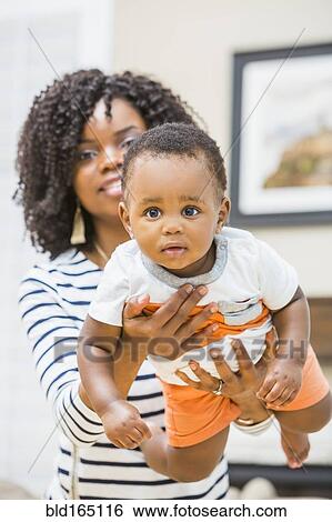 Stock Photograph - Close up of Black mother holding baby son. Fotosearch