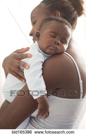 Close up of Black mother holding sleeping baby View Large Photo Image Stock Photograph - Close up of Black mother holding sleeping baby. Fotosearch