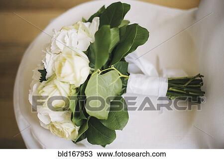 Stock Image - Close up of bouquet of flowers on wedding dress. Fotosearch