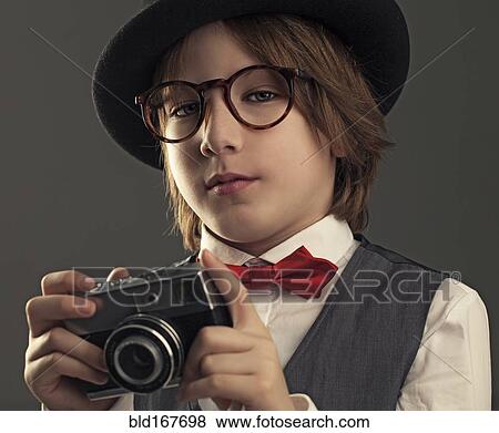 Stock Photo - Close up of boy in hat photographing with vintage camera. Fotosearch