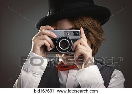 Stock Photo - Close up of boy in top hat photographing with vintage camera. Fotosearch