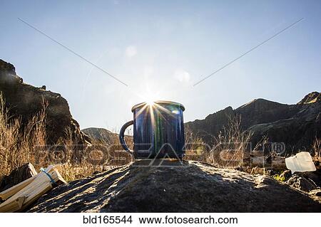Picture - Close up of camping mug under remote mountains. Fotosearch