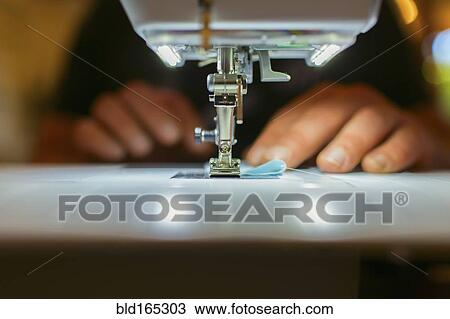 Stock Image - Close up of Caucasian dressmaker using sewing machine. Fotosearch