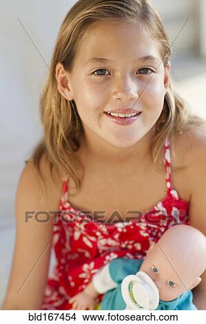 Picture - Close up of Caucasian girl holding baby doll. Fotosearch