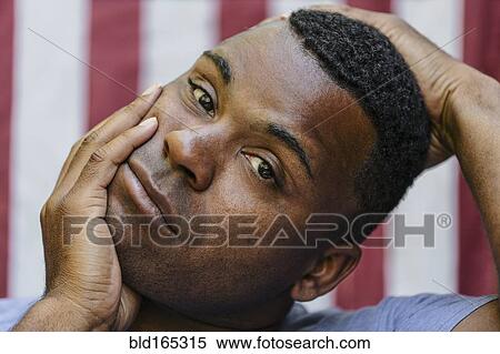 Stock Photography - Close up of concerned Black man in front of American flag. Fotosearch