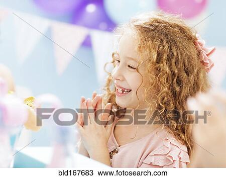 Stock Image - Close up of girl clapping at birthday party. Fotosearch
