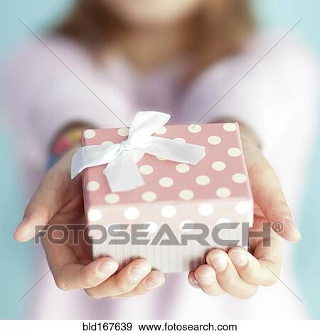 Stock Photo - Close up of girl holding wrapped gift. Fotosearch