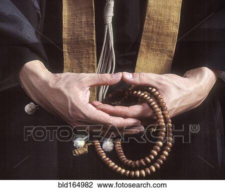 Stock Image - Close up of hands holding Buddhist prayer beads. Fotosearch