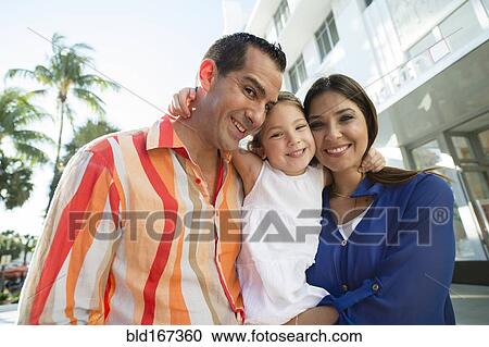 Stock Image - Close up of Hispanic family hugging outdoors. Fotosearch