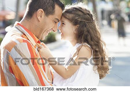 Stock Photo - Close up of Hispanic father and daughter touching foreheads. Fotosearch