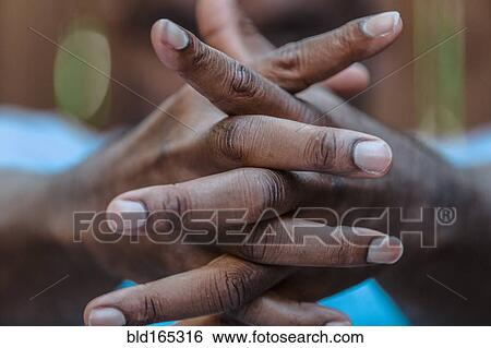 Stock Photograph - Close up of intertwined fingers of Black man. Fotosearch