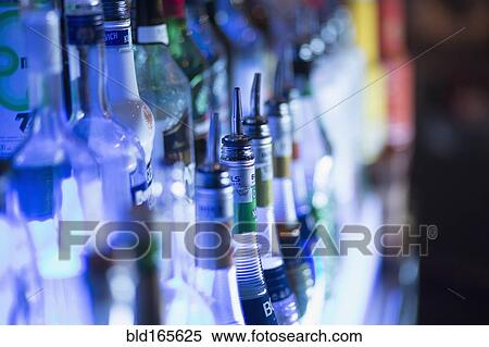 Stock Photography - Close up of liquor bottles illuminated at bar. Fotosearch