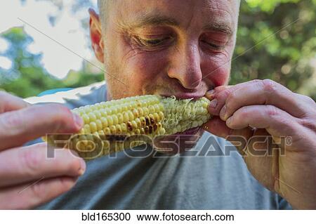 Stock Image - Close up of man eating corn on the cob. Fotosearch