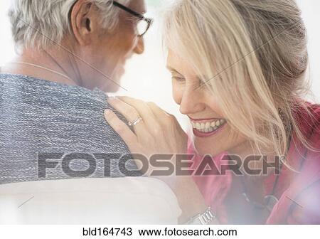 Stock Image - Close up of older Caucasian couple whispering. Fotosearch