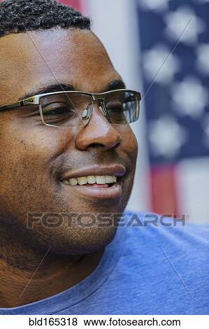 Stock Photo - Close up of smiling Black man in front of American flag. Fotosearch