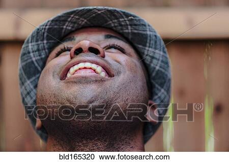 Stock Image - Close up of smiling Black man looking up. Fotosearch