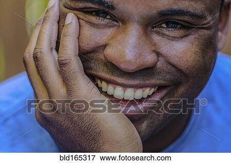 Stock Photo - Close up of smiling Black man resting chin in hand. Fotosearch