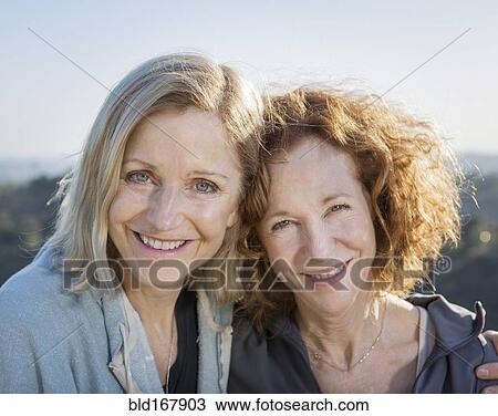 Stock Image - Close up of smiling Caucasian women hugging. Fotosearch