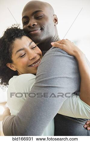 Stock Image - Close up of smiling couple hugging. Fotosearch