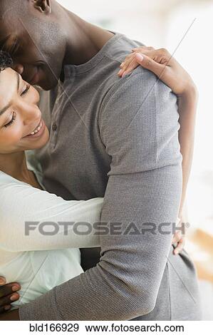 Stock Photo - Close up of smiling couple hugging. Fotosearch