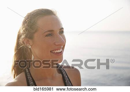 Stock Image - Close up of smiling woman on beach. Fotosearch