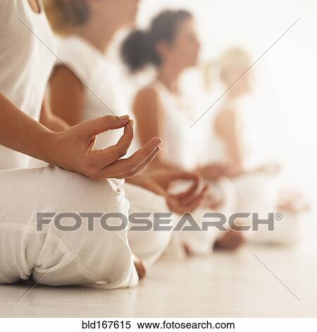 Stock Photography - Close up of women meditating in yoga class. Fotosearch