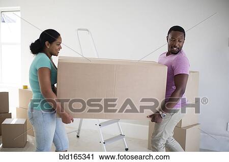 Couple carrying cardboard box in new home View Large Photo Image Stock Image - Couple carrying cardboard box in new home. Fotosearch