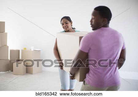 Couple carrying cardboard box in new home View Large Photo Image Stock Image - Couple carrying cardboard box in new home. Fotosearch