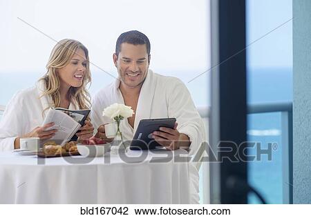 Stock Image - Couple enjoying breakfast on balcony. Fotosearch