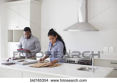 Picture - Couple examining fabric swatches in new home. Fotosearch