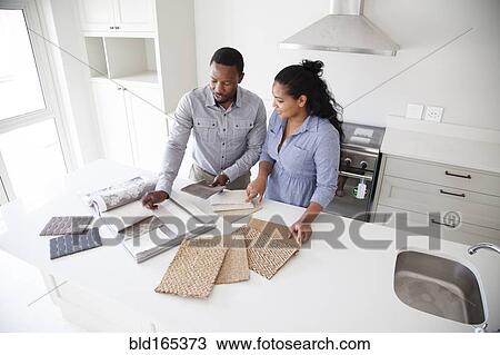Stock Image - Couple examining fabric swatches in new home. Fotosearch