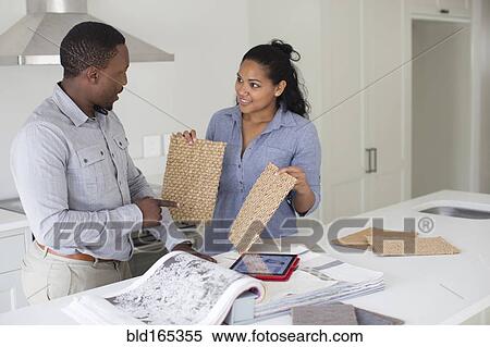 Stock Photography - Couple examining fabric swatches in new home. Fotosearch