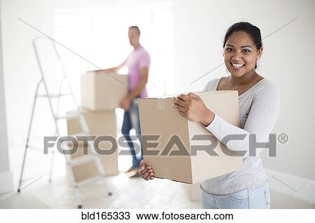 Couple holding cardboard boxes in new home View Large Photo Image Stock Image - Couple holding cardboard boxes in new home. Fotosearch