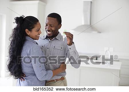 Couple hugging and holding keys in new home View Large Photo Image Stock Image - Couple hugging and holding keys in new home. Fotosearch