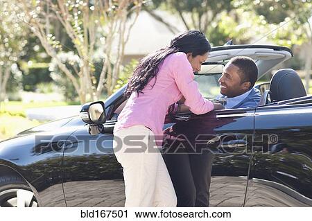 Stock Image - Couple hugging in convertible. Fotosearch