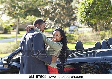 Couple hugging near convertible View Large Photo Image Stock Photo - Couple hugging near convertible. Fotosearch