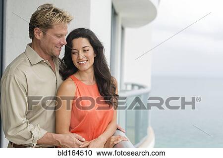 Stock Image - Couple hugging on balcony. Fotosearch