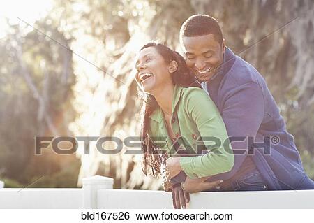 Stock Photograph - Couple hugging on fence. Fotosearch