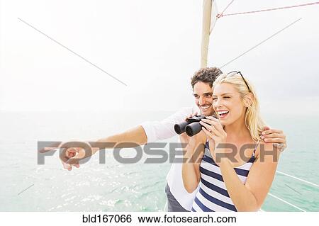 Couple looking out from boat deck with binoculars View Large Photo Image Stock Photograph - Couple looking out from boat deck with binoculars. Fotosearch