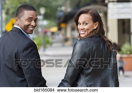 Picture - Couple looking over shoulders in city. Fotosearch