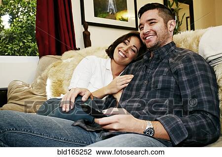 Stock Image - Couple relaxing on sofa in living room. Fotosearch