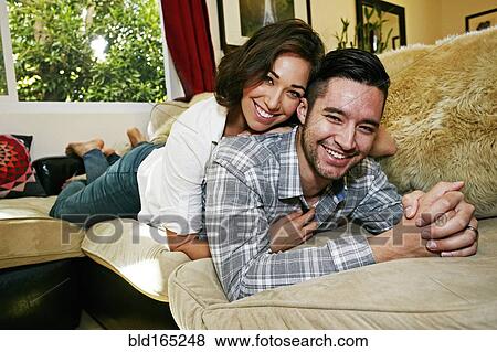 Couple relaxing on sofa in living room View Large Photo Image Stock Photo - Couple relaxing on sofa in living room. Fotosearch