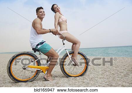 Couple riding bicycle on beach View Large Photo Image Stock Photo - Couple riding bicycle on beach. Fotosearch