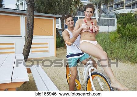 Couple riding bicycle on beach View Large Photo Image Stock Photograph - Couple riding bicycle on beach. Fotosearch