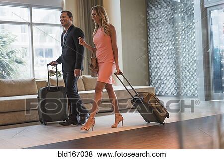 Couple rolling luggage in hotel lobby View Large Photo Image Stock Photo - Couple rolling luggage in hotel lobby. Fotosearch