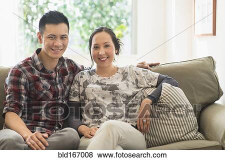 Couple smiling on sofa in living room View Large Photo Image Stock Photo - Couple smiling on sofa in living room. Fotosearch