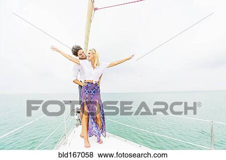 Stock Photo - Couple standing on deck of sailboat. Fotosearch