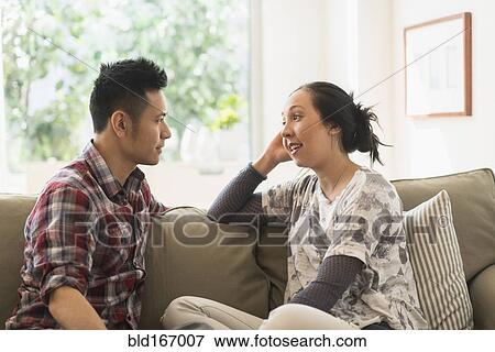 Stock Photo - Couple talking on sofa in living room. Fotosearch