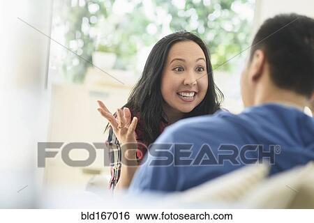 Stock Photograph - Couple talking on sofa in living room. Fotosearch